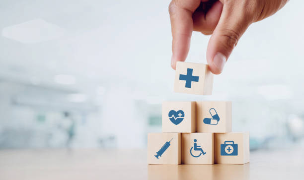Wooden cubes with symbols representing medicine, medications, vaccination, accessibility, and first aid.